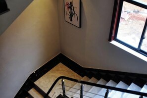 A staircase with a handrail, a framed picture on the wall, and a window with a view of the outside. - Huashu Theme Inn (Wuyuan)