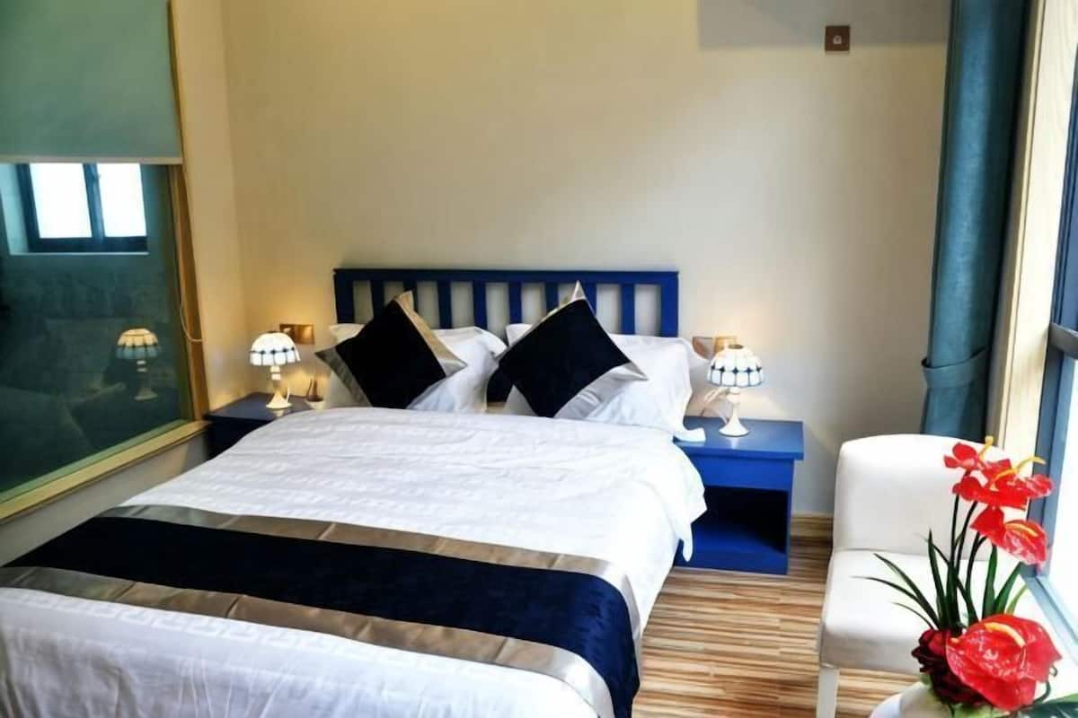 Ein Hotelzimmer mit Bett, Nachttischen, einem Sessel und einem Fenster.