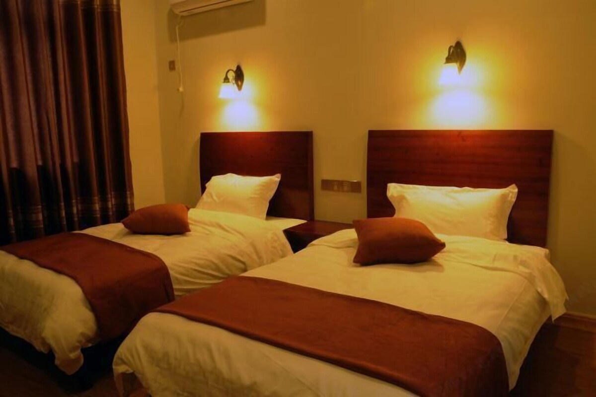 Two beds with headboards, a curtain, and wall-mounted lights.