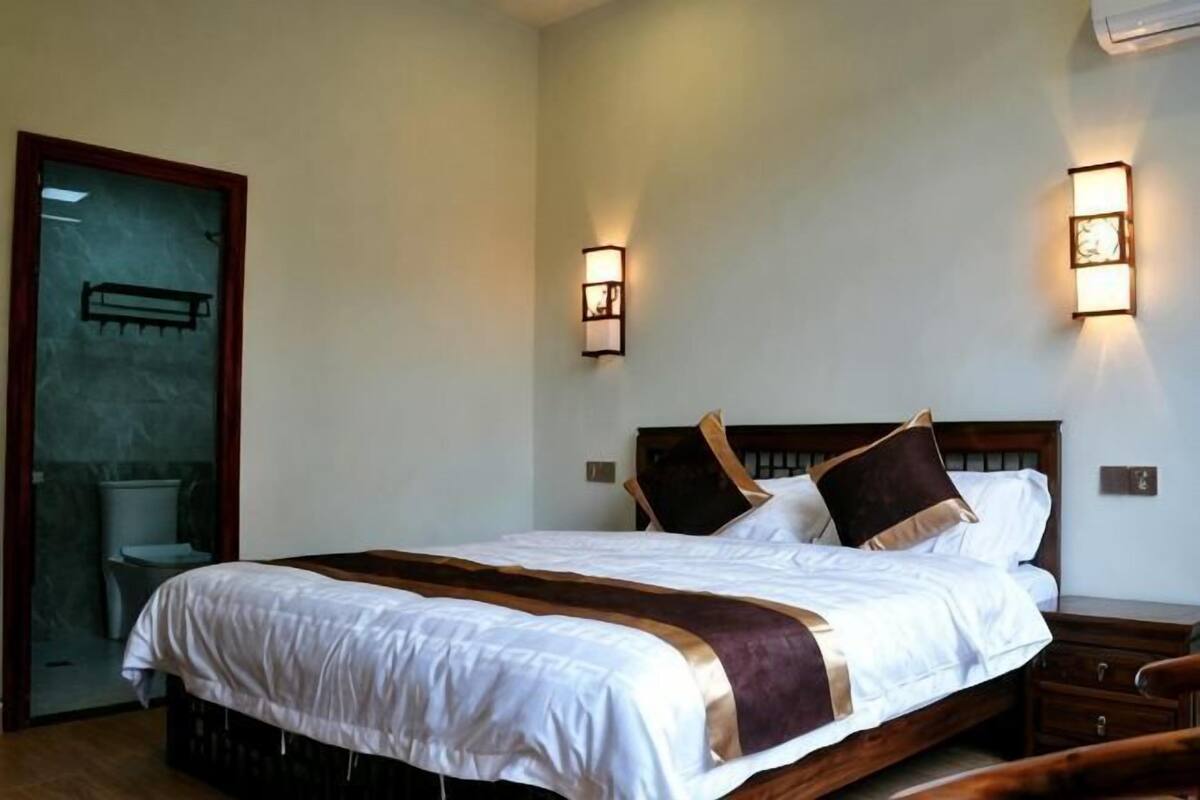 Ein Hotelzimmer mit Bett, Nachttischen, einem Holzkopfteil und Wandleuchten.