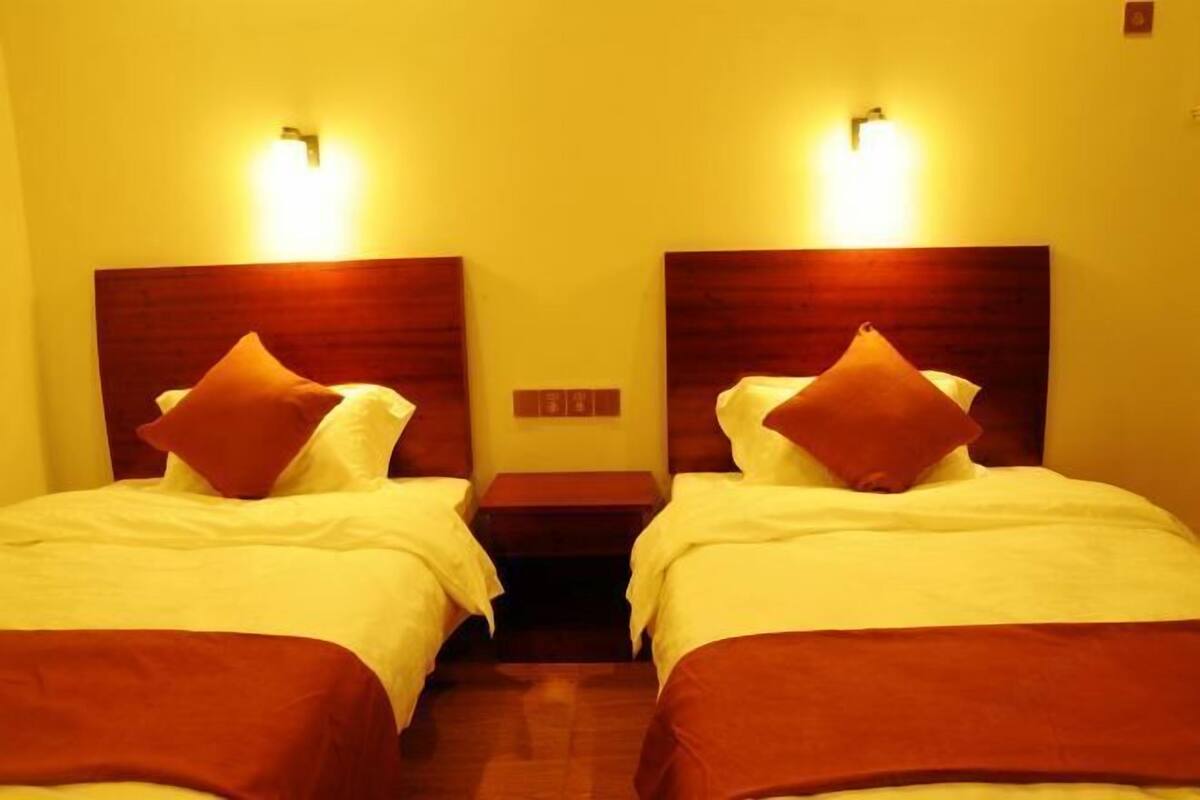 Ein Hotelzimmer mit zwei Betten, jeweils mit einem Holz-Kopfteil und einem Nachttisch.