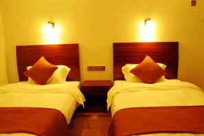 A hotel room with two beds, each with a wooden headboard and a nightstand. - Huashu Theme Inn (Wuyuan)