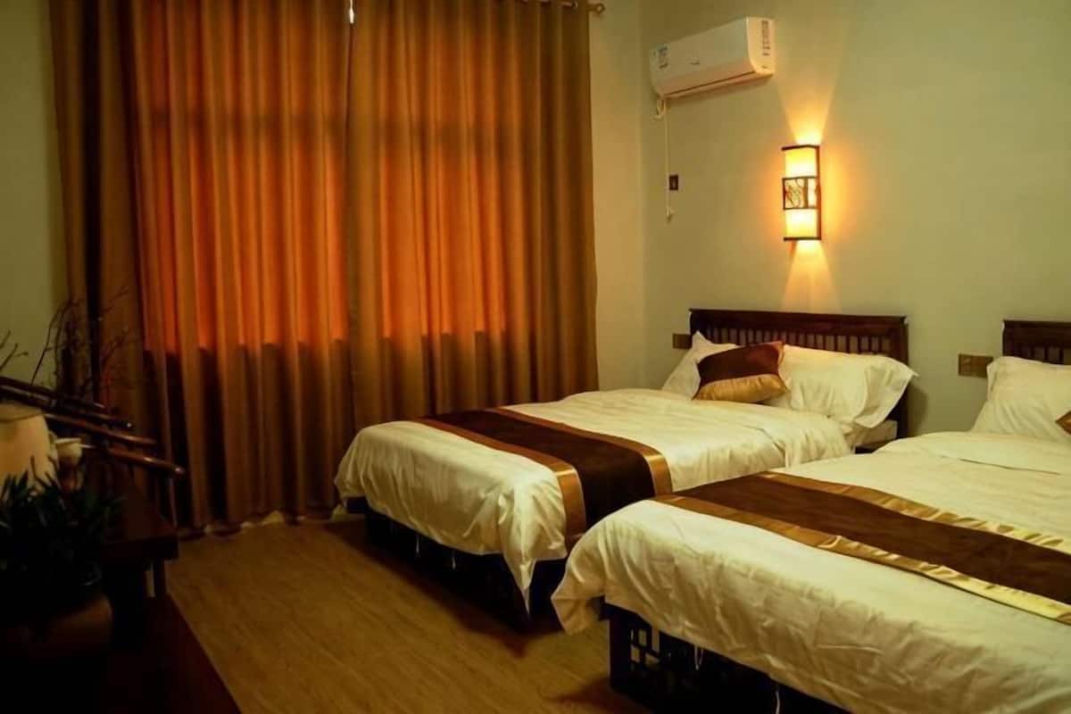 Ein Hotelzimmer mit zwei Betten, einem Schreibtisch, einem Stuhl und einem Vorhangfenster.