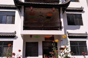 A traditional building with multiple windows, a balcony with a railing, and hanging decorations. - Huashu Theme Inn (Wuyuan)