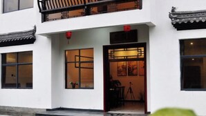 A traditional building with a white facade, a balcony with black railings, and a tiled roof. - Huashu Theme Inn (Wuyuan)
