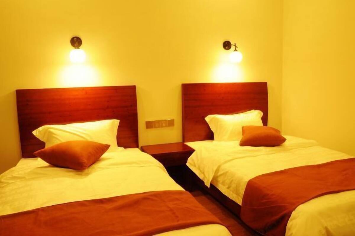 Ein Hotelzimmer mit zwei Betten, jeweils mit einem hölzernen Kopfteil und einem Nachttisch.
