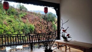 A balcony with a wooden bench and a potted plant. - Huashu Theme Inn (Wuyuan)