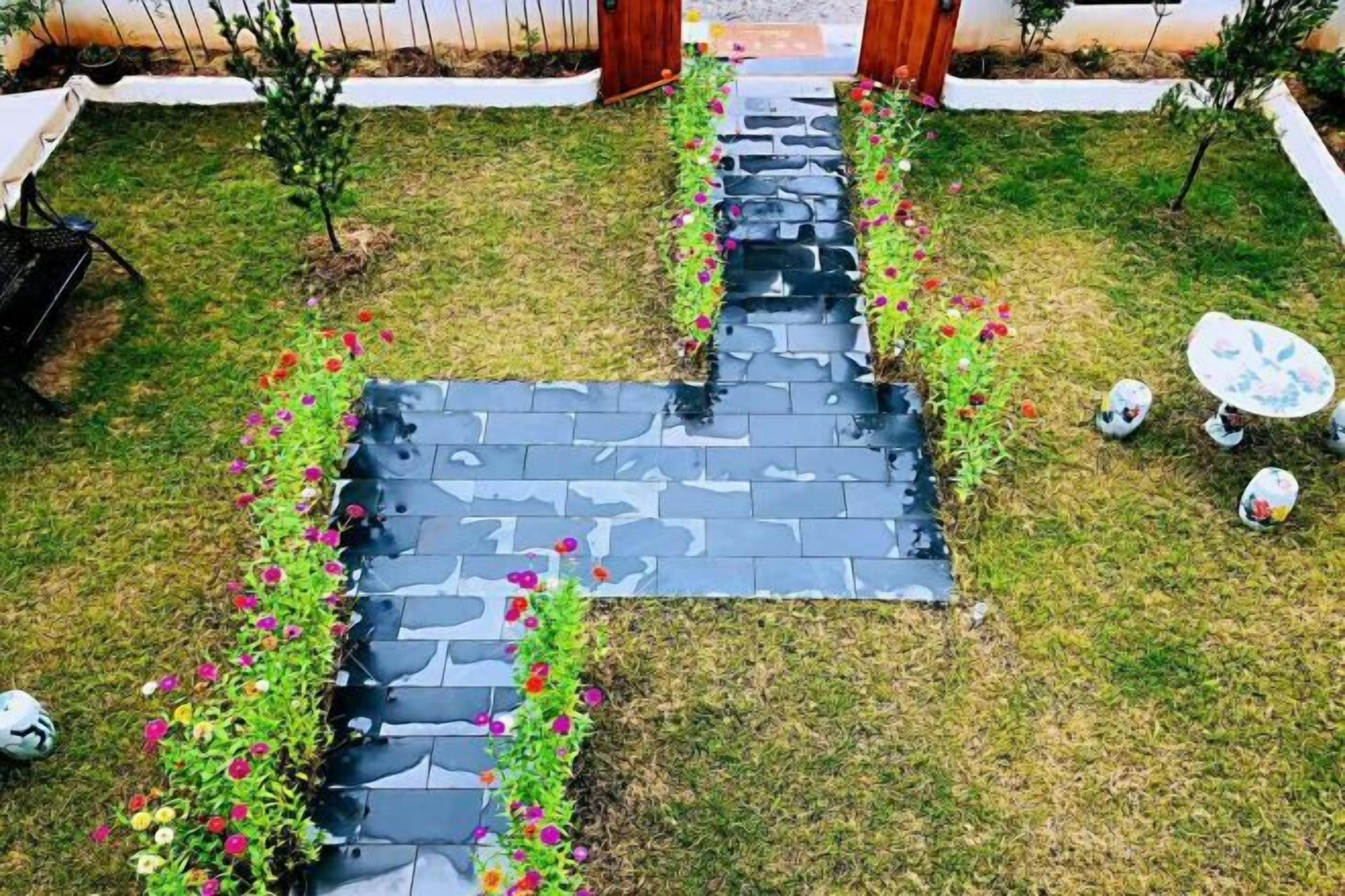 A garden with a paved walkway, small trees, and a table with chairs.