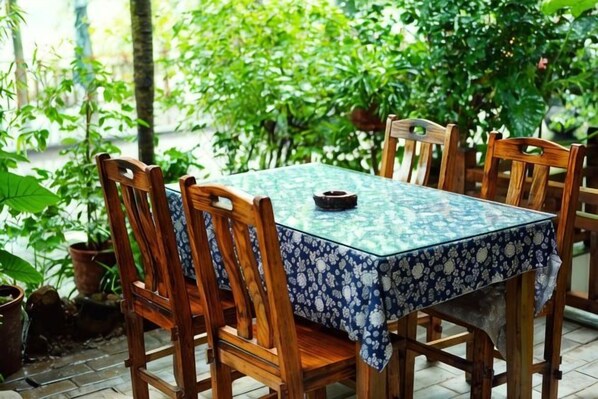 A square table with a patterned tablecloth, surrounded by wooden chairs. - Lijiangyuan Guesthouse (Guilin)