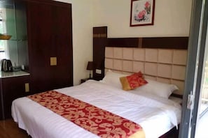 A hotel room with a large bed, a wooden wardrobe, a nightstand, and a framed picture on the wall. - Lijiangyuan Guesthouse (Guilin)