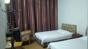 A hotel room with two beds, a desk, a chair, a lamp, and a curtain. - Kangfulai Hotel (Shengzhou)