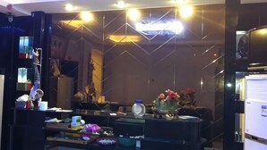 A room with a modern design, featuring a desk with various items, a mirror, and a decorative vase with flowers. - Kangfulai Hotel (Shengzhou)