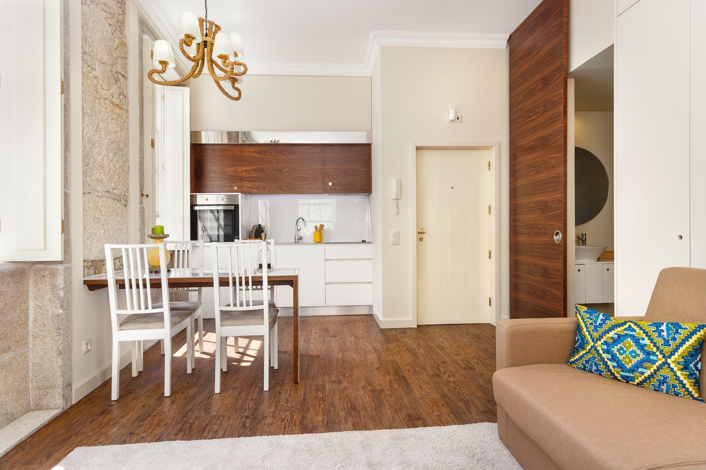 A compact living space with a dining area, kitchenette, and a sofa with a patterned cushion.