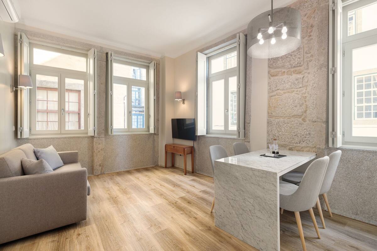 A modern living room with a sofa, dining table, chairs, and a TV.