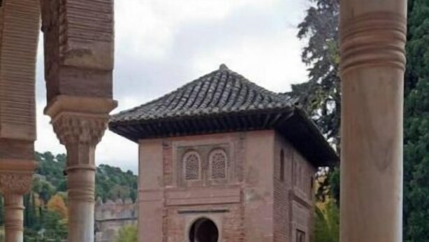 Une cour avec un petit bâtiment, des colonnes et un élément décoratif aquatique.