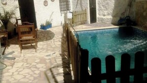 Un espace piscine doté d’un sol en pierre, d’une clôture en bois et d’un parasol blanc.