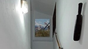 Una escalera con peldaños blancos y largueros marrones, barandilla de madera y un aplique fijado a la pared.