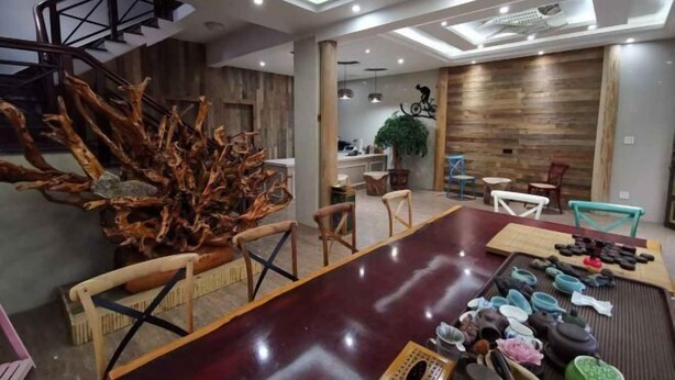 A modern dining area with a large wooden table, chairs, and a decorative tree sculpture.