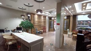 A modern hotel lobby with a reception desk, seating area, and a staircase.