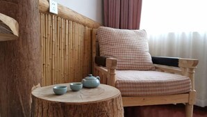 A wooden chair with a checkered cushion, a small round table with two blue bowls, and a bamboo wall panel.