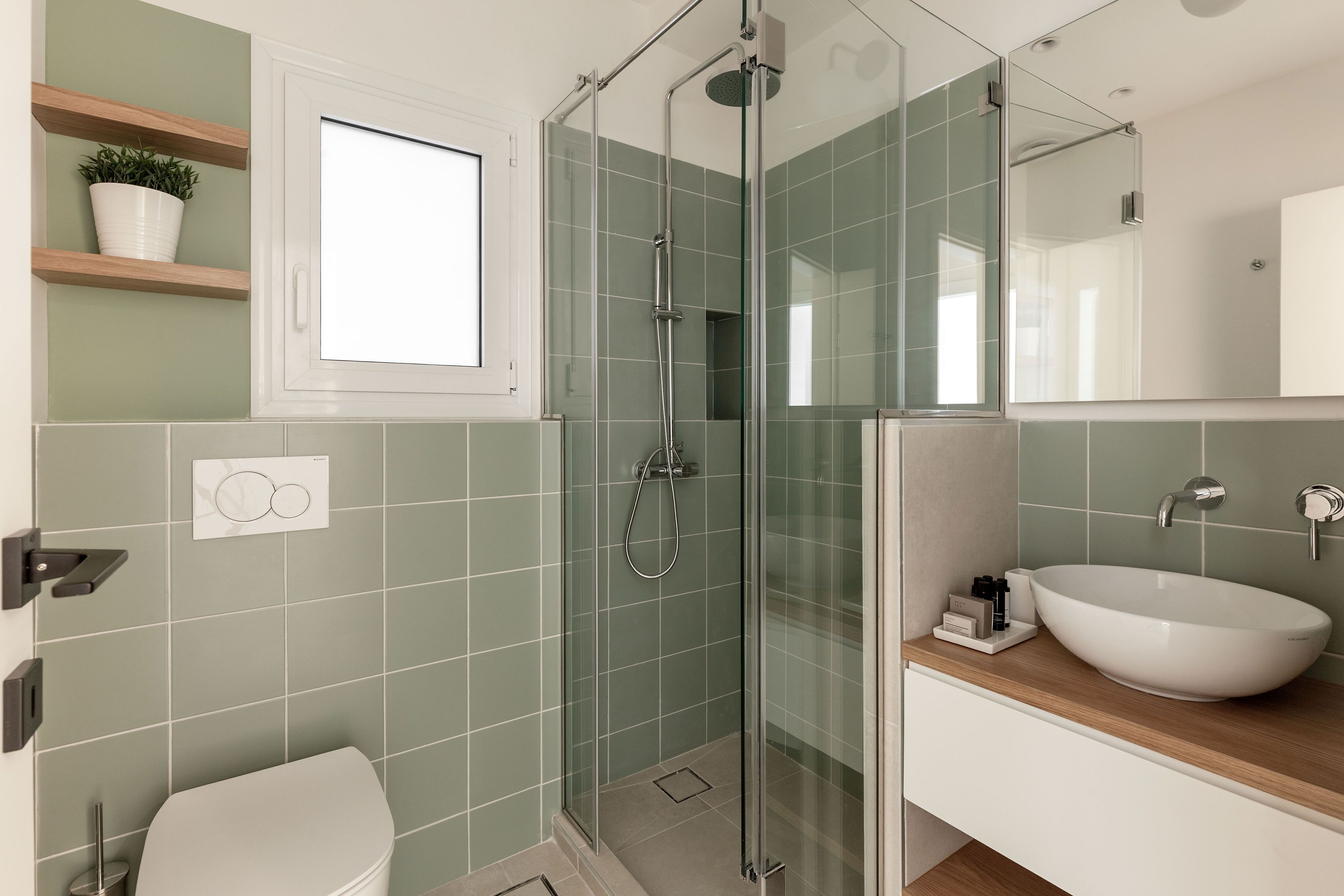 A modern bathroom with a glass-enclosed shower, a white sink, and a toilet.