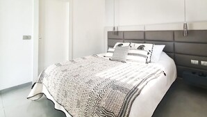 A modern bedroom with a grey headboard, a patterned bedspread, and bedside tables with lamps. - Rupin Ruby in Tel Aviv-yafo (Tel Aviv)