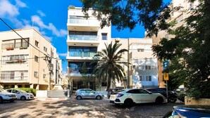 A multi-story residential building with balconies, parked cars, and a palm tree. - Rupin Ruby in Tel Aviv-yafo (Tel Aviv)