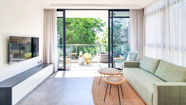 A modern living room with a sofa, a TV, and a balcony with outdoor furniture. - Rupin Ruby in Tel Aviv-yafo (Tel Aviv)