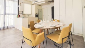 A modern dining area with a round table set for four, surrounded by yellow chairs. - Rupin Ruby in Tel Aviv-yafo (Tel Aviv)