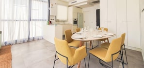 A modern dining area with a round table set for four, surrounded by yellow chairs.