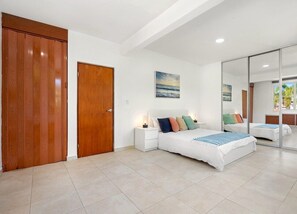 A bedroom with a large bed, a wooden wardrobe, a nightstand, and a painting on the wall. - Puerto Rico Ocean Park Loft Vacation Rental With Parking Otium Rentals (San Juan)