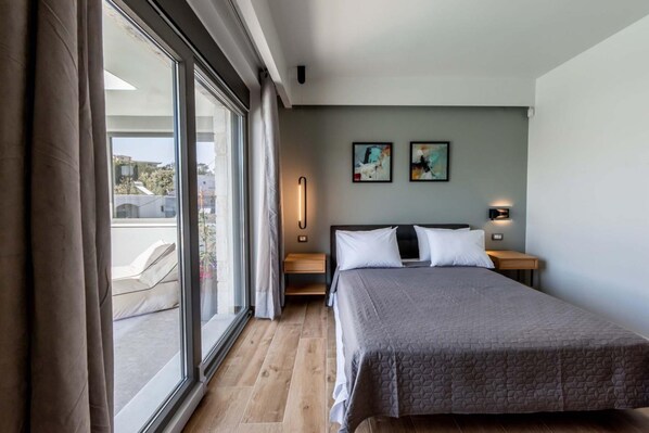A modern hotel room with a large bed, a nightstand, a wall-mounted lamp, and artwork on the wall. - Lusol Seafront Villa I-free Heated Pool 100m Sea (Chania)