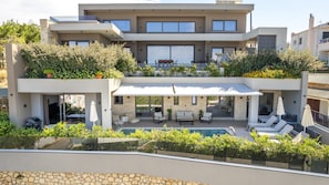 Uma casa moderna de dois andares com um jardim no telhado, piscina e área de estar ao ar livre.