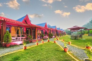 Una hilera de edificios con techos rojos, zonas de estar al aire libre y macetas con plantas.
