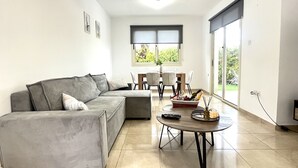 Una sala moderna con un sofá seccional gris, una mesa redonda y un comedor con mesa y sillas.