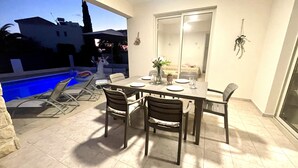 Un espacio al aire libre para comer con piscina, sillas y una mesa lista para cuatro.