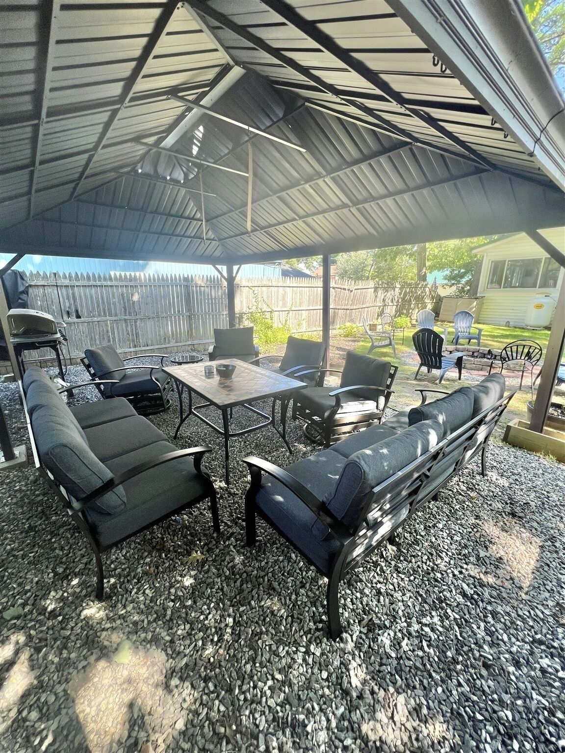 An outdoor patio area with a covered seating arrangement, including a table and chairs, and a built-in bench.