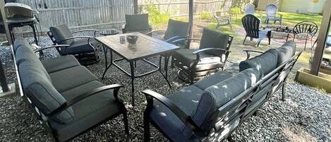 An outdoor patio area with a covered seating arrangement, including a table and chairs, and a built-in bench.