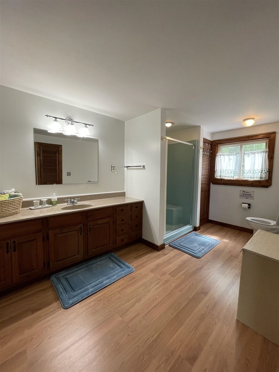 A modern bathroom with a large mirror, wooden cabinets, a sink, and a shower.