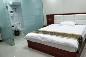A hotel room with a bed, a bedside table, a bathroom with a toilet and shower.