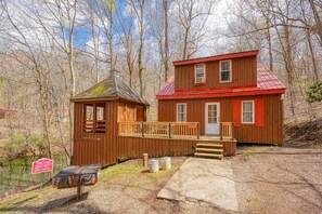 A cabin with a wooden exterior, a red roof, and a dock extending into a body of water.