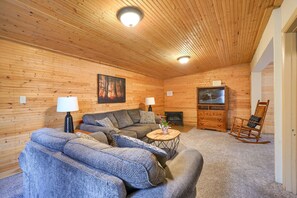 A cozy log cabin interior with a sofa set, a television, and a fireplace.