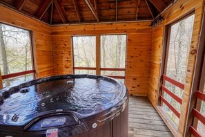 Eine Holzdiele mit Whirlpool, großen Fenstern und einer Holzterrasse.