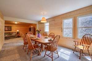 Een kamer met houten lambrisering, waarin een eettafel voor zes personen staat gedekt, omringd door houten stoelen.