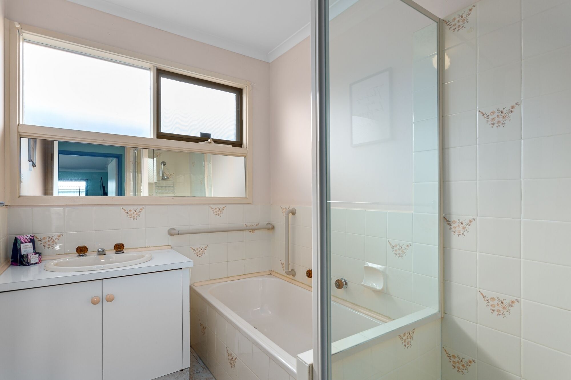 A bathroom with a bathtub, a sink, and a glass shower enclosure.