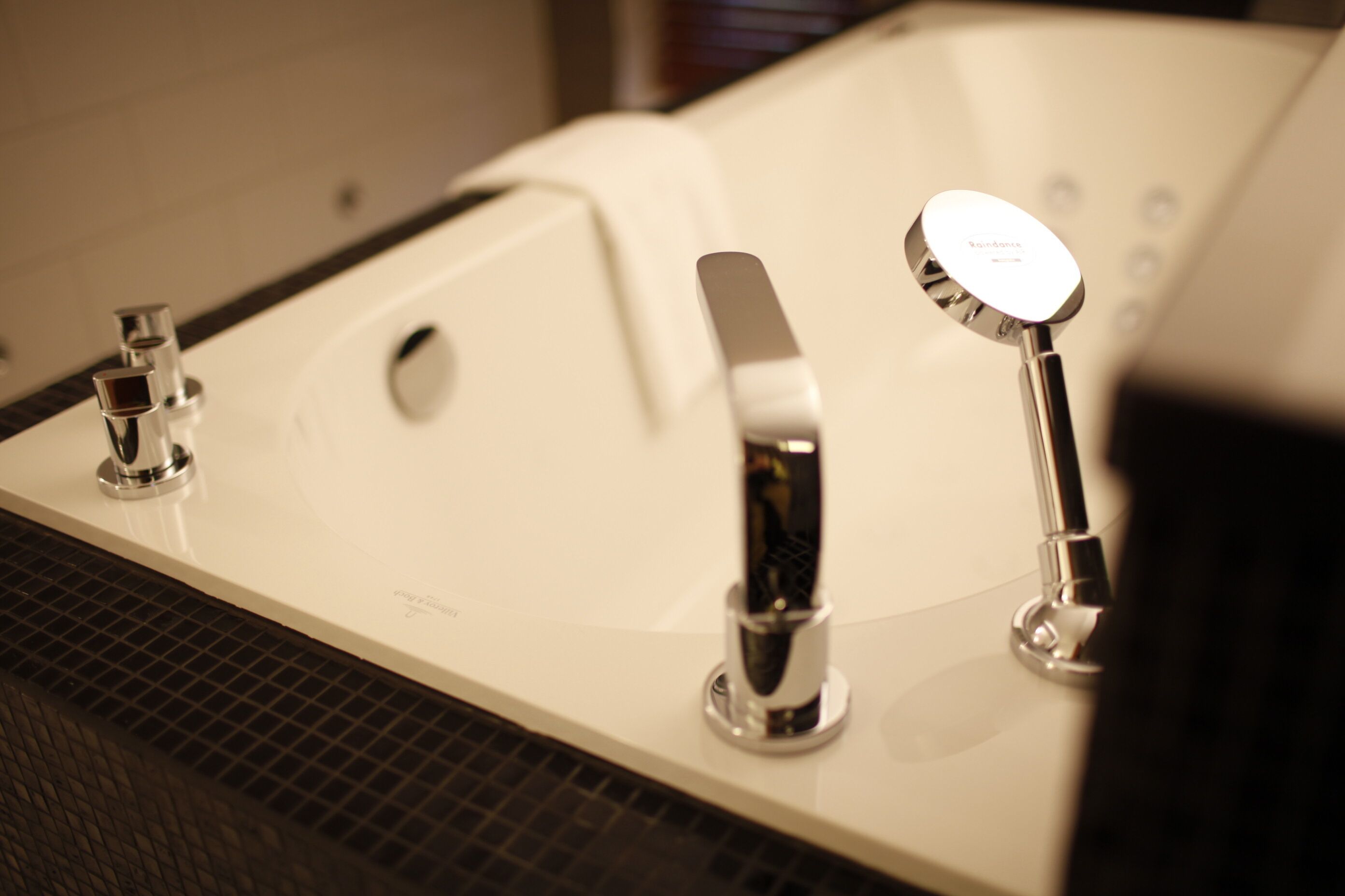 A modern bathroom with a large bathtub, two faucets, and a showerhead.