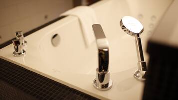 A modern bathroom with a large bathtub, two faucets, and a showerhead.