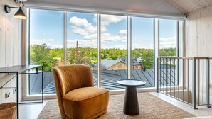 A modern balcony with a leather chair, a small round table, and a view of a forested area with buildings in the background. - Billnäsin ruukki (Raseborg)