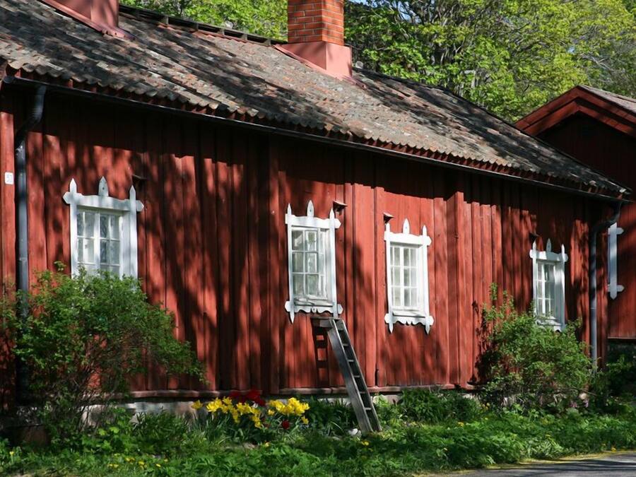 Una casa de madera roja con ventanas de marco blanco y una chimenea.