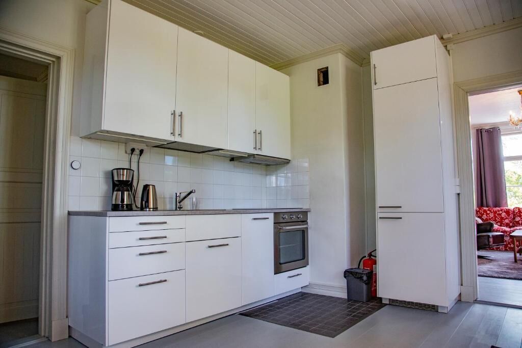 A modern kitchen with white cabinets, a built-in oven, and a coffee maker.